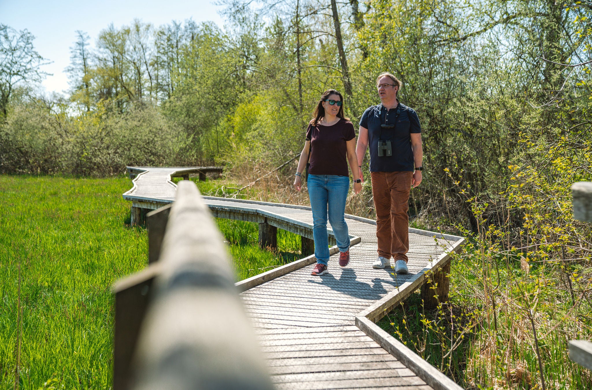 Ein Paar läuft über einen Holzsteg im BirdLife Neeracherried.